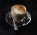 A cappuccino glass with a spoon, black background