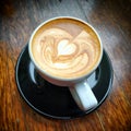 Cappuccino heart coffee art on dark wood background