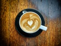 Cappuccino heart coffee art on dark wood background