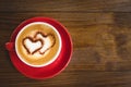 Cappuccino or Latte coffee with heart shape in red cup on table. Royalty Free Stock Photo