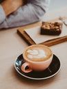 Cappuccino or latte with frothy foam in ceramic coffee cup and brownie cake on table Royalty Free Stock Photo