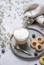 Cappuccino or latte with milk foam in a cup with homemade berry cookies and blueberries on a light background with gypsophila