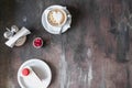 Cappuccino with latteart, piece of mousse cake with pink macaroon. Copy space on a dark wooden table in a coffee shop