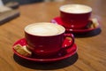 Cappuccino with lush foam and pattern in red ceramic cup