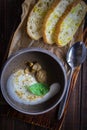 Cappuccino soup with boletus on wooden cutting board. Three slices of white bread and a spoon on the brown wooden background in Royalty Free Stock Photo