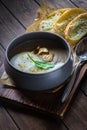 Cappuccino soup with mushrooms on wooden cutting board. Three slices of white bread and a spoon on the brown wooden background in Royalty Free Stock Photo