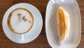 cappuccino in white coffee cup and bread on wood table, coffee t