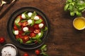 Caprese - italian salad with red tomatoes and mozzarella cheese with green basil leaves. Top view, wooden table Royalty Free Stock Photo