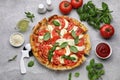 Delicious Caprese pizza with tomatoes, mozzarella and basil on light grey table, flat lay