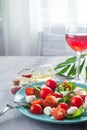 Caprese salad. Healthy meal with cherry tomatoes, mozzarella balls, spices, fresh rocket and basil with red wine on Royalty Free Stock Photo