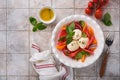 Caprese salad. Italian caprese salad with sliced tomatoes, mozzarella cheese, basil, olive oil in white plate over white backgroun Royalty Free Stock Photo