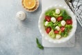 Caprese salad. Italian caprese salad with sliced tomatoes, mozzarella cheese, basil, olive oil in white plate over white backgroun Royalty Free Stock Photo