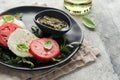 Caprese salad. Italian caprese salad with sliced tomatoes, mozzarella cheese, arugula basil olive oil in black plate over old Royalty Free Stock Photo