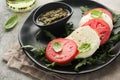 Caprese salad. Italian caprese salad with sliced tomatoes, mozzarella cheese, arugula, basil, olive oil in black plate over old Royalty Free Stock Photo