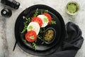 Caprese salad. Italian caprese salad with sliced tomatoes, mozzarella cheese, arugula, basil, olive oil in black plate over old Royalty Free Stock Photo