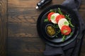 Caprese salad Italian caprese salad with sliced tomatoes mozzarella cheese arugula basil olive oil in black plate over old wooden Royalty Free Stock Photo