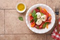 Caprese salad. Italian caprese salad with sliced tomatoes, mozzarella cheese, basil, olive oil in white plate over old brick tiles Royalty Free Stock Photo