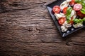 Caprese Salad.Mediterranean salad. Mozzarella cherry tomatoes basil and olive oil on old oak table. Italian cuisine