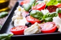 Caprese Salad.Mediterranean salad. Mozzarella cherry tomatoes basil and olive oil on old oak table. Italian cuisine