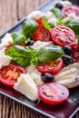 Caprese Salad.Mediterranean salad. Mozzarella cherry tomatoes basil and olive oil on old oak table. Italian cuisine