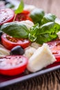 Caprese Salad.Mediterranean salad. Mozzarella cherry tomatoes basil and olive oil on old oak table. Italian cuisine