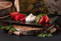 Caprese salad. Mozzarella cheese, tomatoes and basil herb leaves on black plate over wood cuts, stone table in a Royalty Free Stock Photo