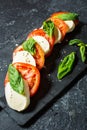 Caprese salad. Mozzarella cheese, tomatoes and basil herb leaves over stone table. Royalty Free Stock Photo