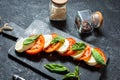 Caprese salad. Mozzarella cheese, tomatoes and basil herb leaves over stone table. Royalty Free Stock Photo