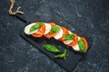 Caprese salad. Mozzarella cheese, tomatoes and basil herb leaves over stone table Royalty Free Stock Photo