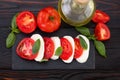 Caprese salad. Mozzarella cheese, tomatoes and basil herb leaves over stone table. Top view Royalty Free Stock Photo