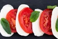 Caprese salad. Mozzarella cheese, tomatoes and basil herb leaves over stone table. Top view Royalty Free Stock Photo