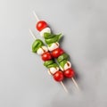 Caprese salad with mozzarella, cherry tomatoes and basil on skewers on a gray background