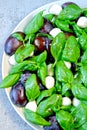 Caprese salad with plums. Fruity caprese. Healthy salad with basil and plums on a plate. A plate with a useful salad.