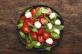 Caprese salad with ripe red tomatoes and mozzarella cheese with fresh green basil leaves. Italian food. Top view, wooden Royalty Free Stock Photo