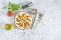 Caprese salad with sliced fresh tomatoes, mozzarella cheese and basil served on a white plate on light gray table surface, top Royalty Free Stock Photo