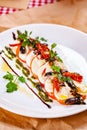 Caprese salad with tomatoes, mozzarella cheese, pesto sauce and black olives on white plate Royalty Free Stock Photo