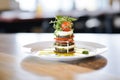 caprese stack tower in the center of a round white plate, balsamic aside