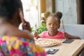 Capricious little girl with fancy hairstyle can`t wait for eating pizza.