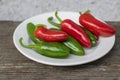 Capsicum annuum Jalapeno chilli hot peppers, group of green and red fruits on wooden brown table on white plate Royalty Free Stock Photo