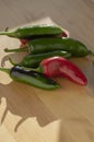 Capsicum annuum Jalapeno chilli hot peppers, group of green and red fruits on light brown wooden background Royalty Free Stock Photo