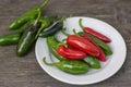 Capsicum annuum Jalapeno chilli hot peppers, group of green and red fruits on wooden brown table on white plate Royalty Free Stock Photo