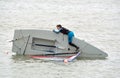 Capsized Sailing Dinghy with young man try to right it, in the sea at Felixstowe Suffolk England. Royalty Free Stock Photo