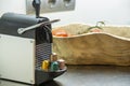 Capsule coffee machine on a black worktop, fruit bowl with tomatoes and capsules of various types Royalty Free Stock Photo