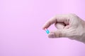 Capsule medicine in hand with pink background