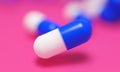 Capsule medicine pills, health pharmacy concept. Drugs for treatment medication. Heap of blue white color capsules on pink backgro Royalty Free Stock Photo