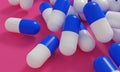 Capsule medicine pills, health pharmacy concept. Drugs for treatment medication. Heap of blue white color capsules on pink backgro