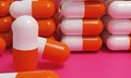 Capsule medicine pills, health pharmacy concept. Drugs for treatment medication. Heap of orange white color capsules on pink backg Royalty Free Stock Photo