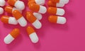 Capsule medicine pills, health pharmacy concept. Drugs for treatment medication. Heap of orange white color capsules on pink backg Royalty Free Stock Photo