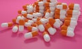 Capsule medicine pills, health pharmacy concept. Drugs for treatment medication. Heap of orange white color capsules on pink backg Royalty Free Stock Photo