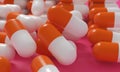 Capsule medicine pills, health pharmacy concept. Drugs for treatment medication. Heap of orange white color capsules on pink backg Royalty Free Stock Photo